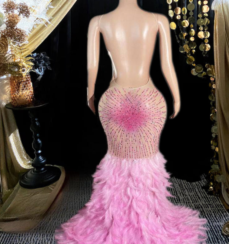 A stunning pink maxi dress with rhinestone accents and feather detailing, perfect for elegant occasions.