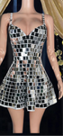 Woman wearing a shimmering mirror dress reflecting light, standing in a festival-like setting.