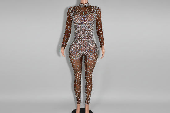 Mannequin wearing a sparkling, long-sleeve jumpsuit in front of a decorative mirror.