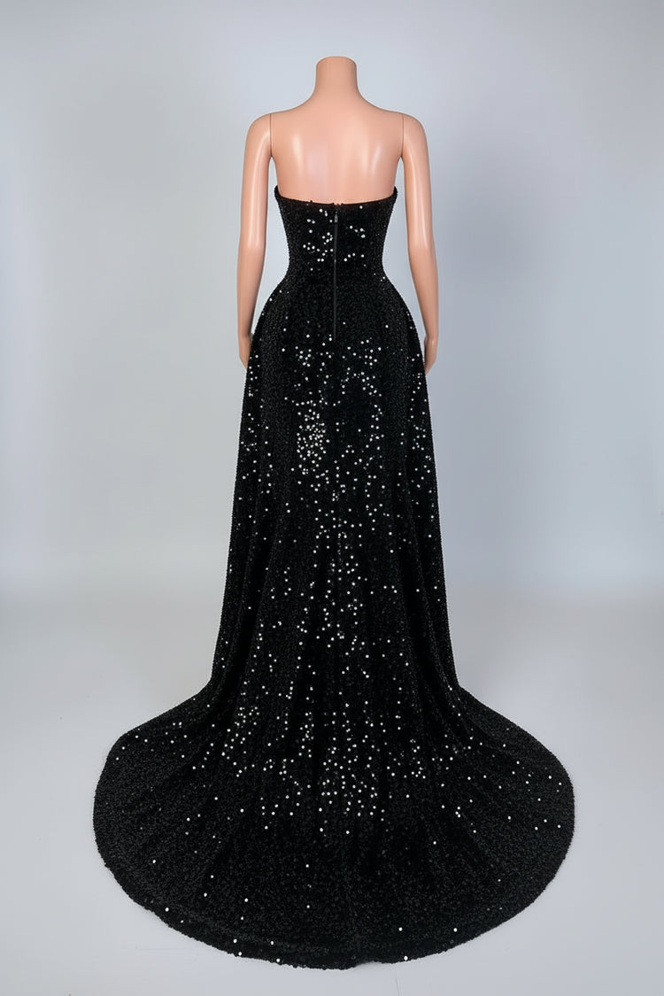 Black strapless evening gown with a long train on a mannequin against a decorative wall.