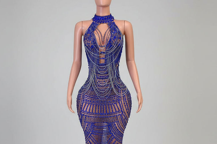 Mannequin wearing a blue beaded dress with intricate designs in front of a decorative mirror.