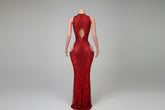 Red evening gown with cut-out design on a mannequin against a decorative wall.