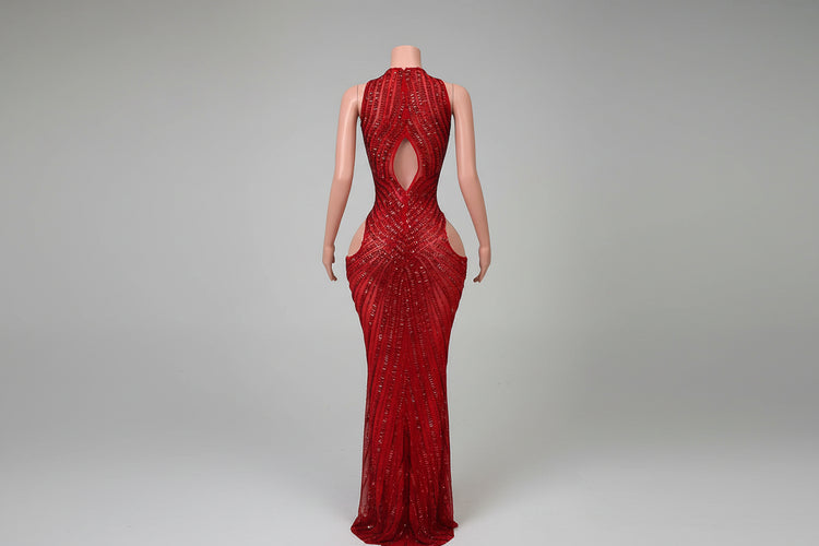 Red evening gown with cut-out design on a mannequin against a decorative wall.