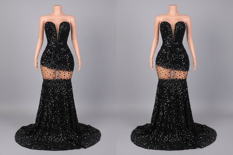 Black sequin evening gown on a mannequin against a decorative wall.