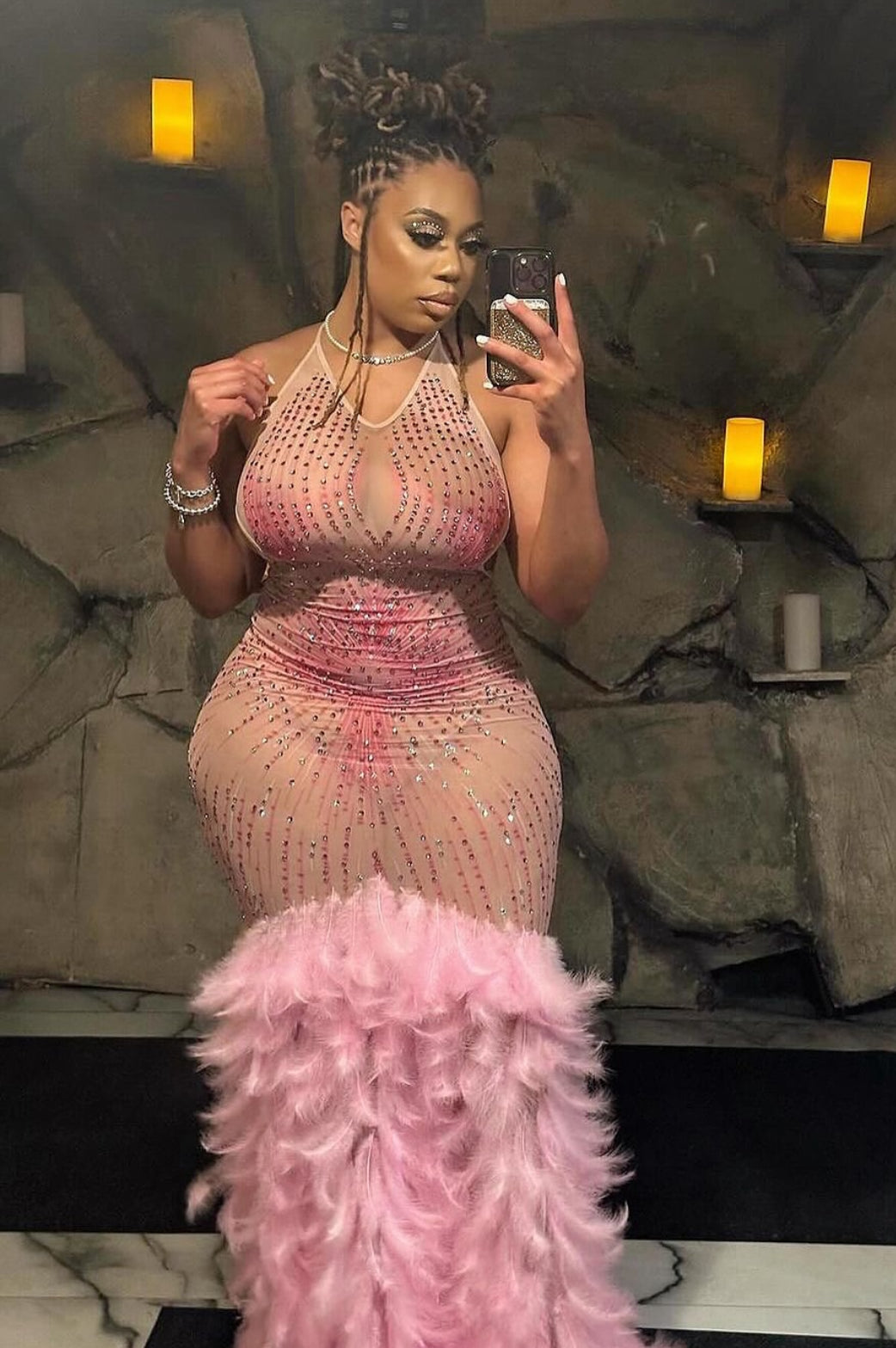 A stunning pink maxi dress with rhinestone accents and feather detailing, perfect for elegant occasions.