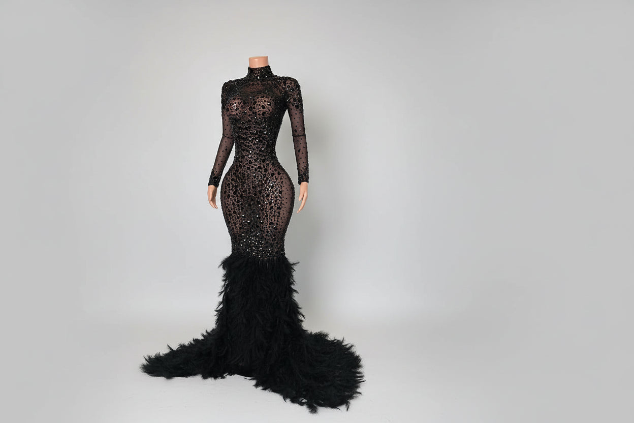 Black lace evening gown with feathered skirt on a mannequin against a white wall.