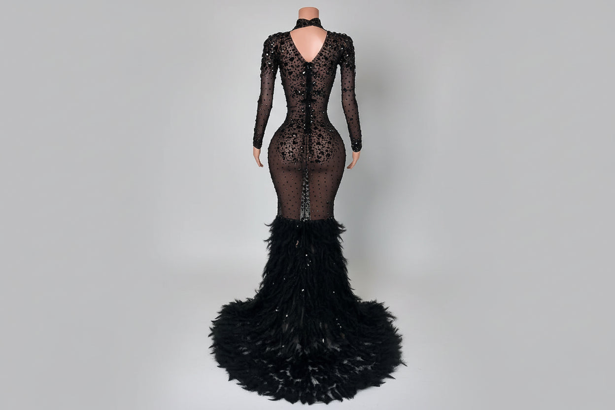 Black lace evening gown with feathered skirt on a white marble floor.