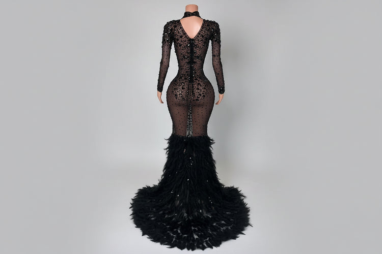 Black lace evening gown with feathered skirt on a white marble floor.